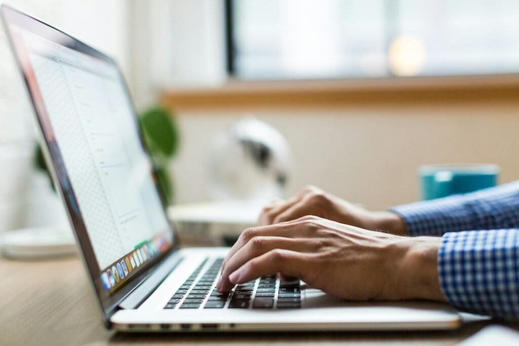 Small business owner typing on a laptop while comparing AEO vs GEO vs SEO for search and AI visibility
